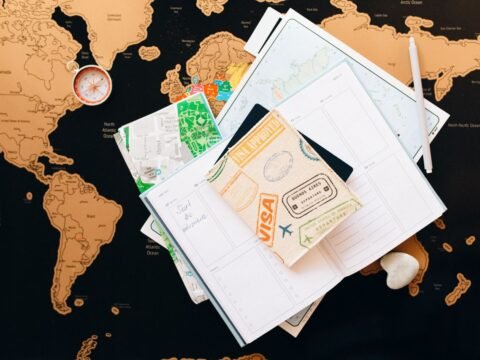 Passport with visa stamp, world map and travel planner for choosing the right visa before volunteering abroad