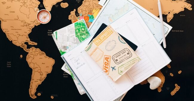 Passport with visa stamp, world map and travel planner for choosing the right visa before volunteering abroad