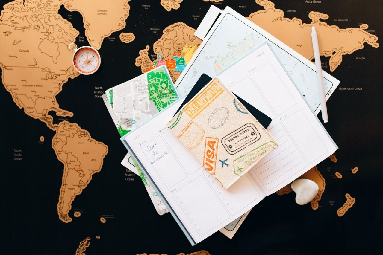 Passport with visa stamp, world map and travel planner for choosing the right visa before volunteering abroad