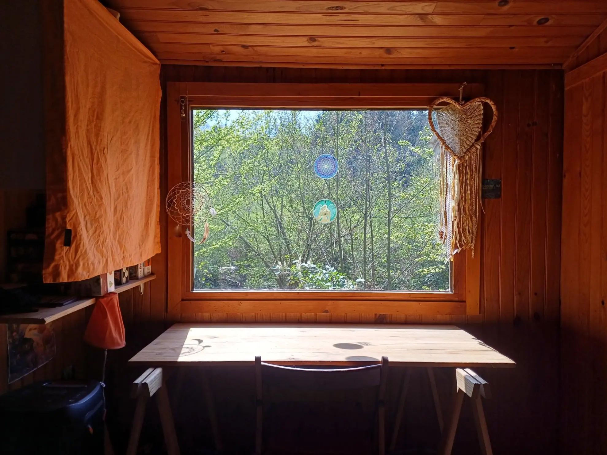Wooden interior with a desk by a large window overlooking nature at a simple living volunteer project in rural Belgium