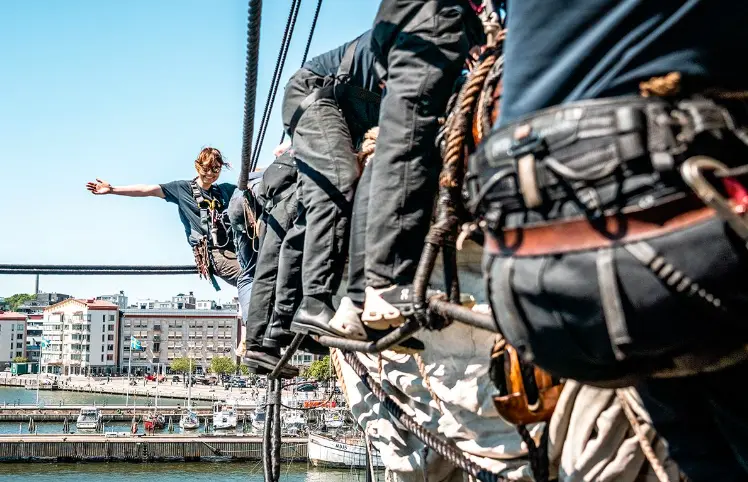 Volunteers wearing safety harnesses on the rigging of the Götheborg ship in Gothenburg, Sweden, during a tall ship volunteering experience.