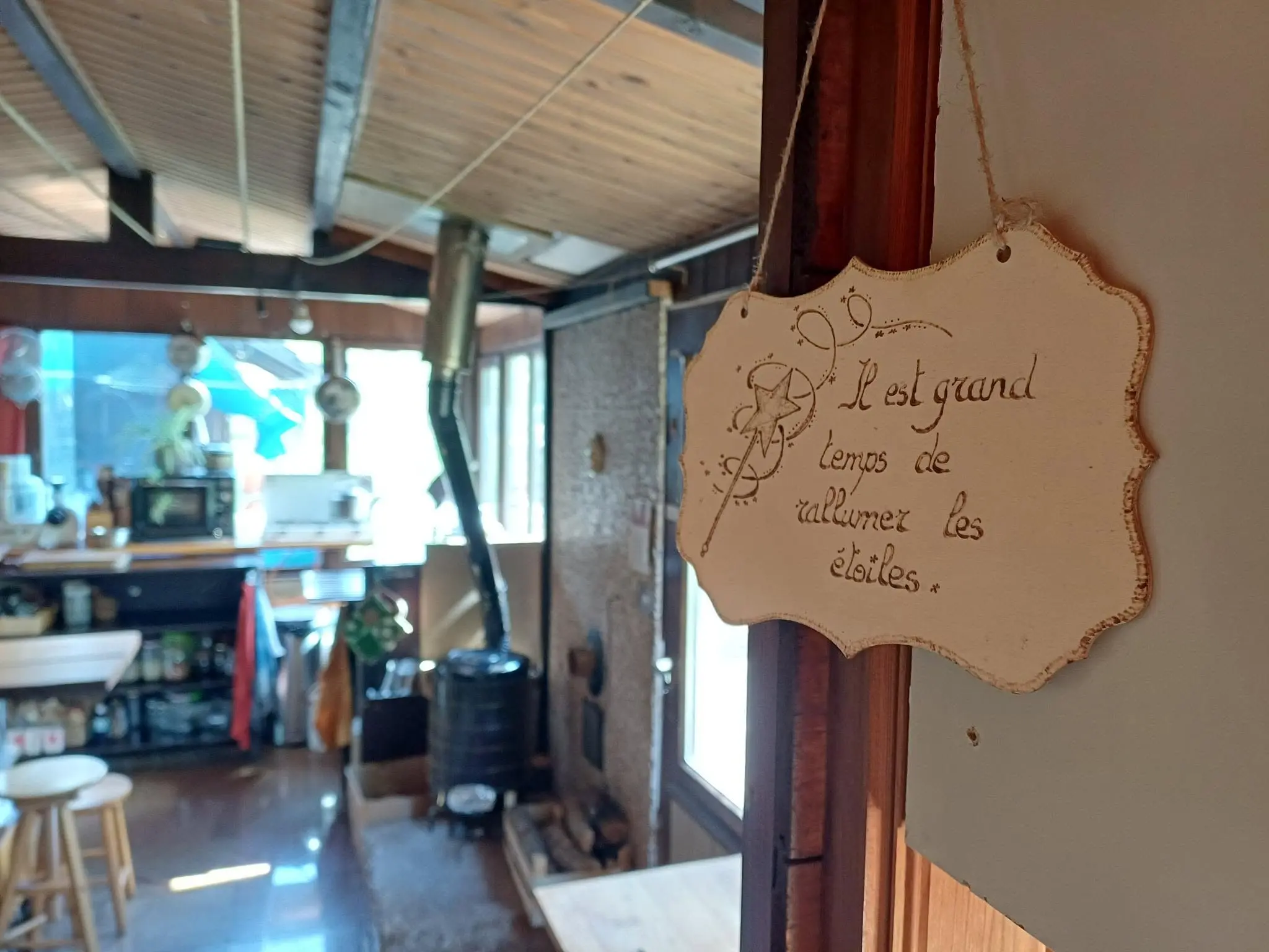 Wooden chalet interior with a French quote sign, wood stove and simple living atmosphere at a rural volunteer stay in Belgium