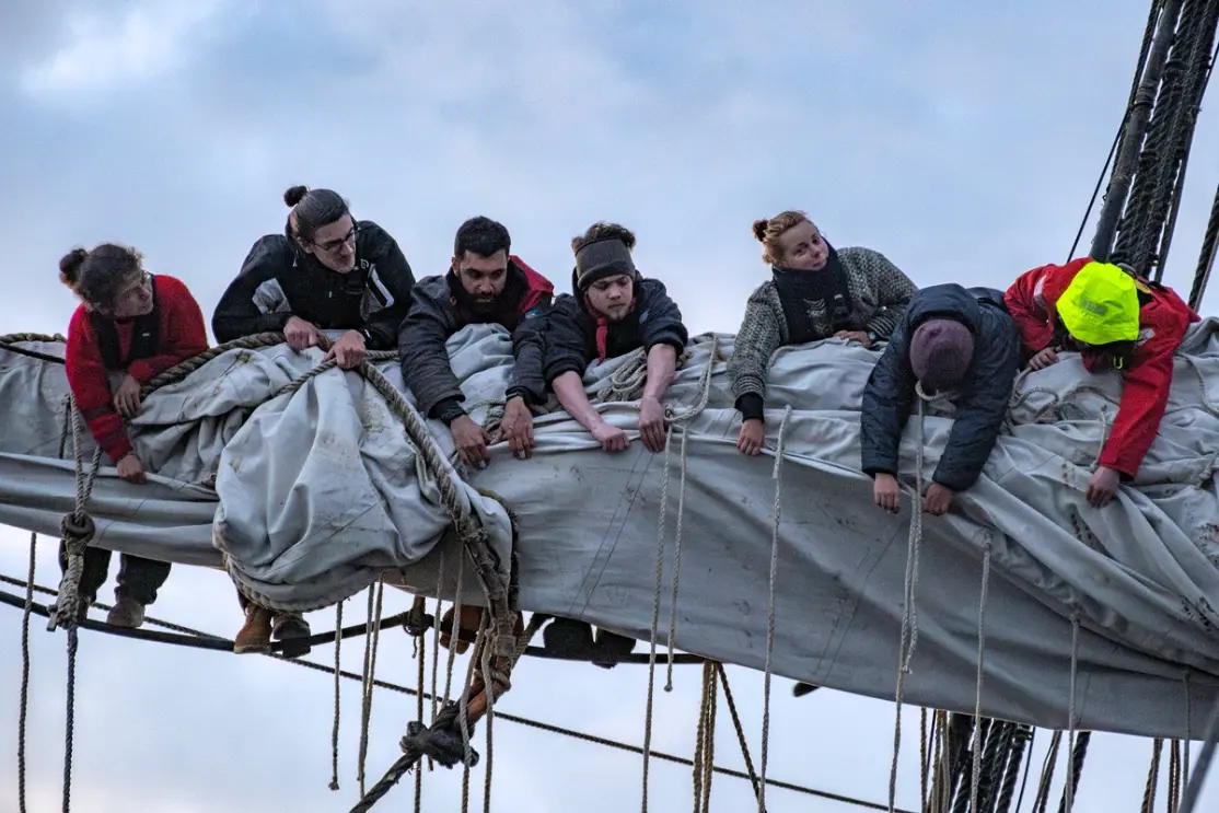 Volunteers working with sails and ropes high on the Götheborg ship in Sweden, part of a hands-on ship volunteer opportunity in Gothenburg.