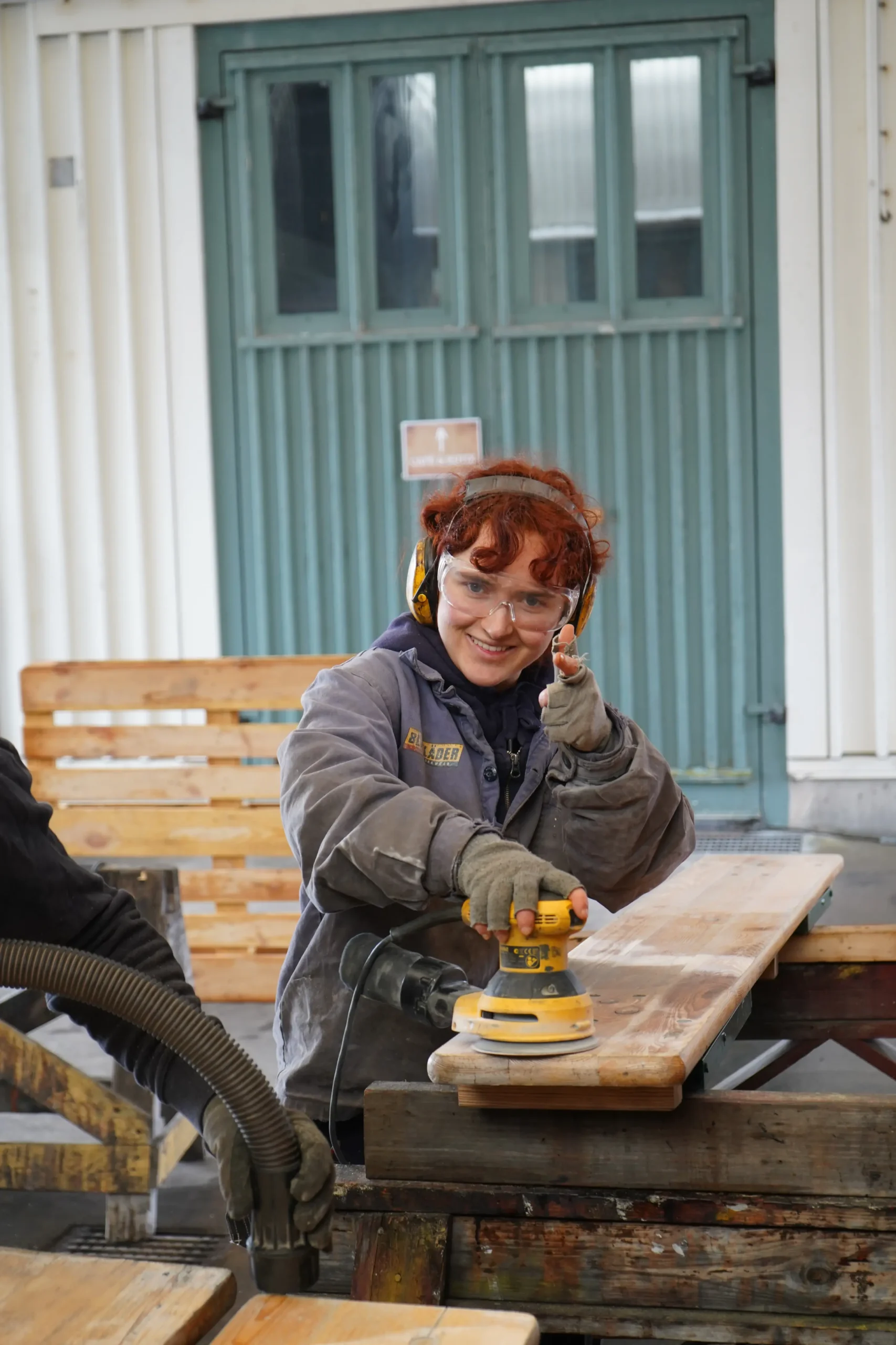 Volunteer sanding wood while working aboard the Götheborg historic ship in Sweden, showing hands-on ship maintenance during a volunteer opportunity in Gothenburg.
