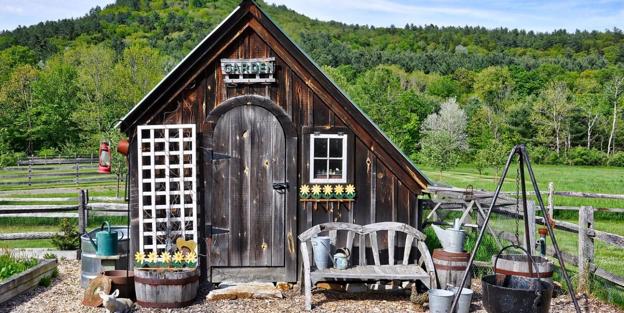 Rustic wooden garden shed in a rural landscape, used to illustrate the Carya Grove off-grid community in Missouri