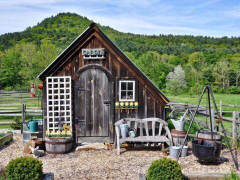 Rustic wooden garden shed in a rural landscape, used to illustrate the Carya Grove off-grid community in Missouri