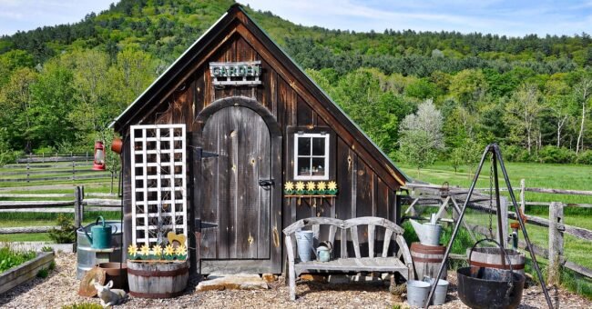 Rustic wooden garden shed in a rural landscape, used to illustrate the Carya Grove off-grid community in Missouri