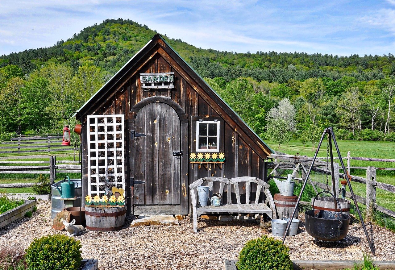 Rustic wooden garden shed in a rural landscape, used to illustrate the Carya Grove off-grid community in Missouri