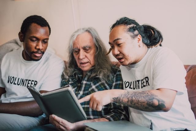Volunteers and an older man looking through a book during a community support activity