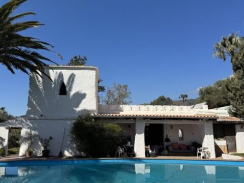 White retreat center with swimming pool, palm trees, and mountain views in the Alpujarras of southern Spain.