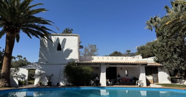 White retreat center with swimming pool, palm trees, and mountain views in the Alpujarras of southern Spain.
