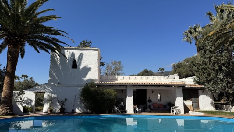 White retreat center with swimming pool, palm trees, and mountain views in the Alpujarras of southern Spain.