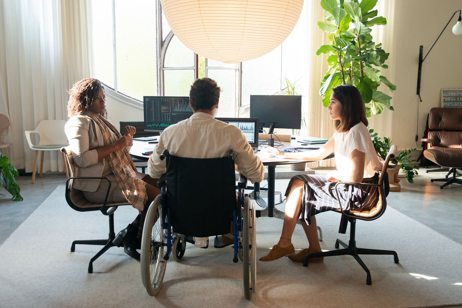 A diverse group taking part in a collaborative meeting in an accessible workplace, including a wheelchair user. Featured image for the Voluntouring.org guide about inclusive volunteering, accessibility, flexible participation and removing barriers for volunteers.