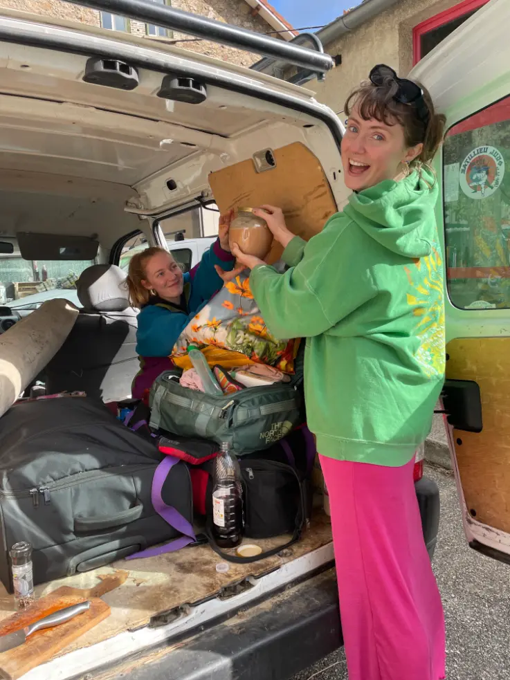 Two volunteers unpacking belongings from a van during their stay at a rural goat farm in Ardèche, France