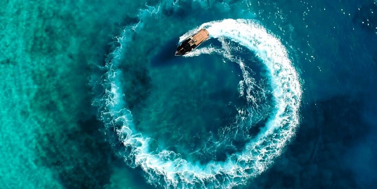 Aerial view of a motorboat on turquoise water during a coastal tourism work exchange in Himara, Albania
