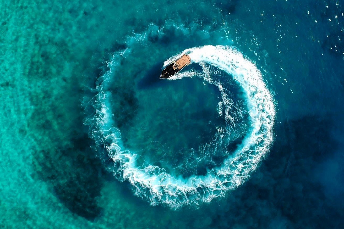 Aerial view of a motorboat on turquoise water during a coastal tourism work exchange in Himara, Albania