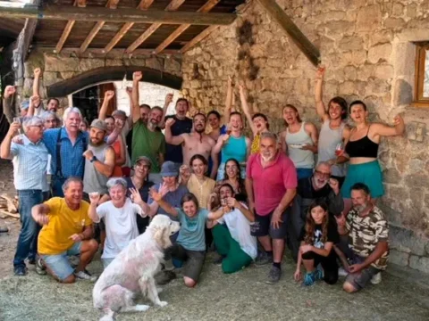 Group of volunteers, friends and family outside a stone farm building during a farm volunteering experience in Ardèche, France