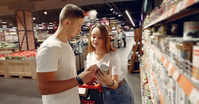 Two shoppers examining a packaged food product in a supermarket aisle.