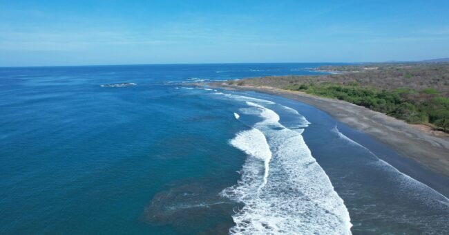 Aerial view of the Pacific coastline near Marbella, Guanacaste, Costa Rica, with waves breaking along the beach.